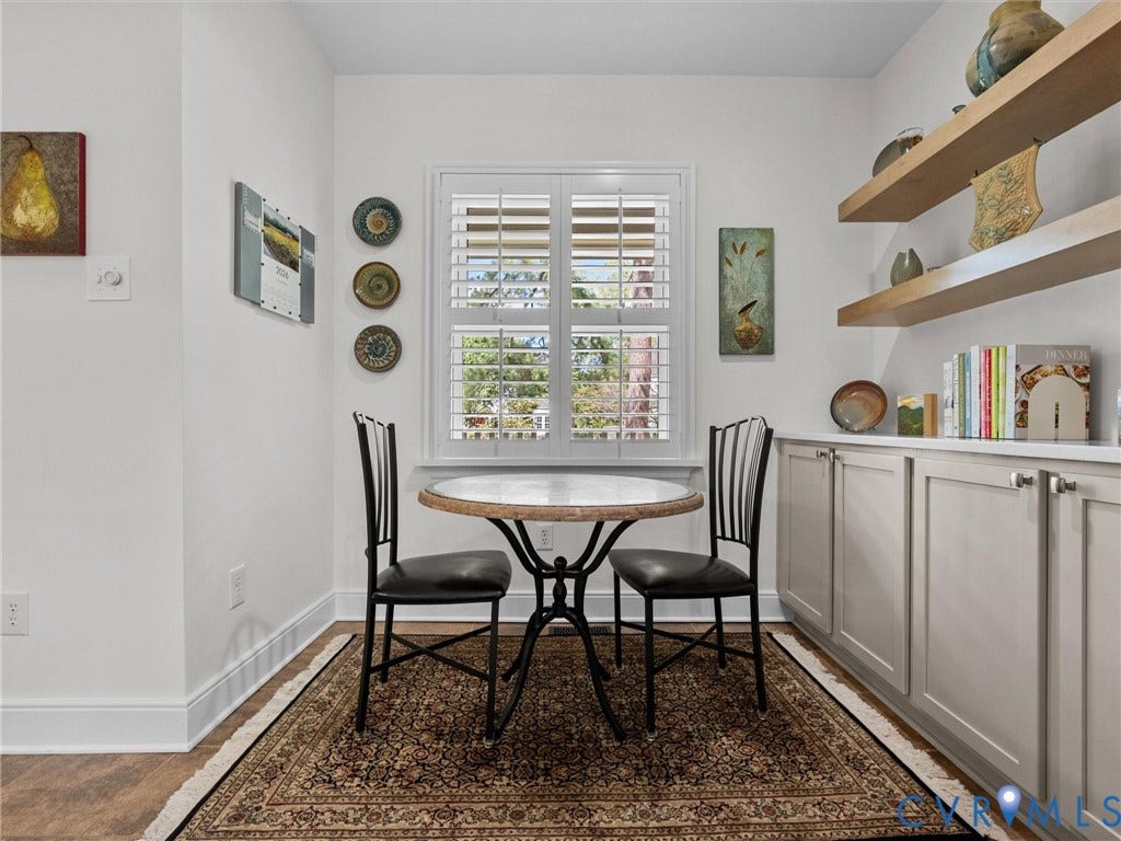 7723 Stuart Hall Road, Rollingwood Terrace, Henrico, VA 23229 White plantation shutters, built-in lower cabinetry with silver hardware, upper wood-finish shelving, wood-finish flooring, and white wall finishes