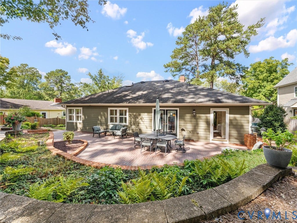 7723 Stuart Hall Road, Rollingwood Terrace, Henrico, VA 23229 Expansive brick paver patio with a low stone retaining wall, featuring exterior siding, multiple windows, and two glass entry doors