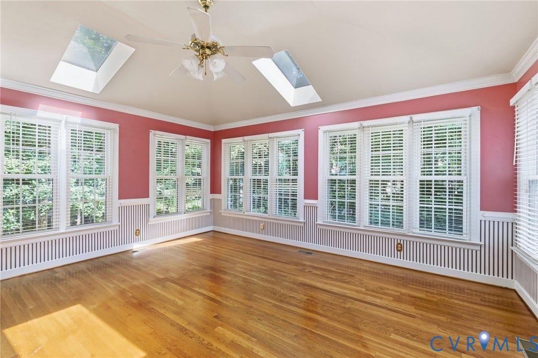 Hardwood flooring, multiple windows with blinds, two skylights, ceiling fan, and wainscoting