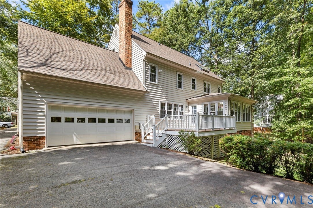 Light-toned siding exterior with a brick chimney and a multi-pane garage door