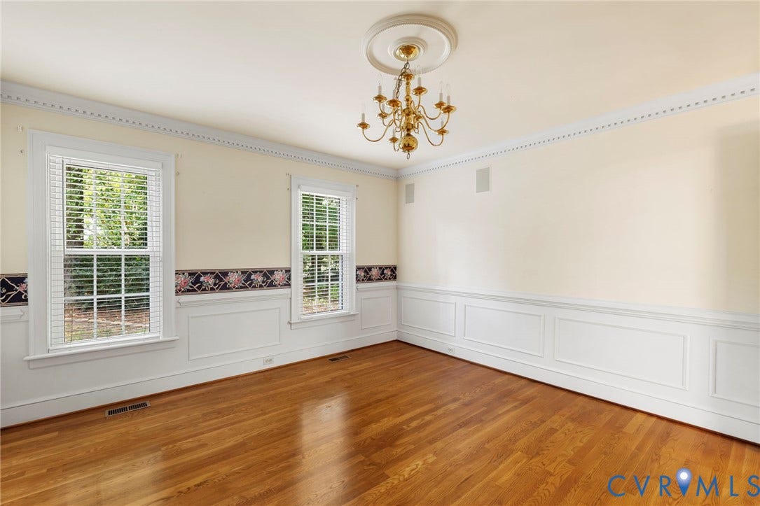 Hardwood flooring, decorative wainscoting, crown molding, double hung windows, and a chandelier with ceiling medallion