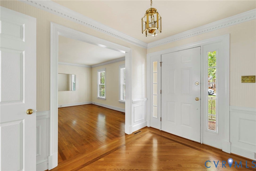 Entryway featuring a paneled door with sidelights, wood-finish flooring, wainscoting, decorative crown molding, and an overhead brass-finish lantern fixture