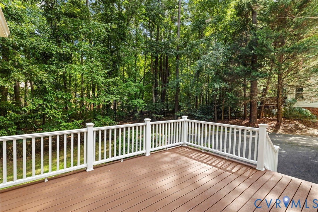 Expansive outdoor deck featuring wood-finish flooring and white railings