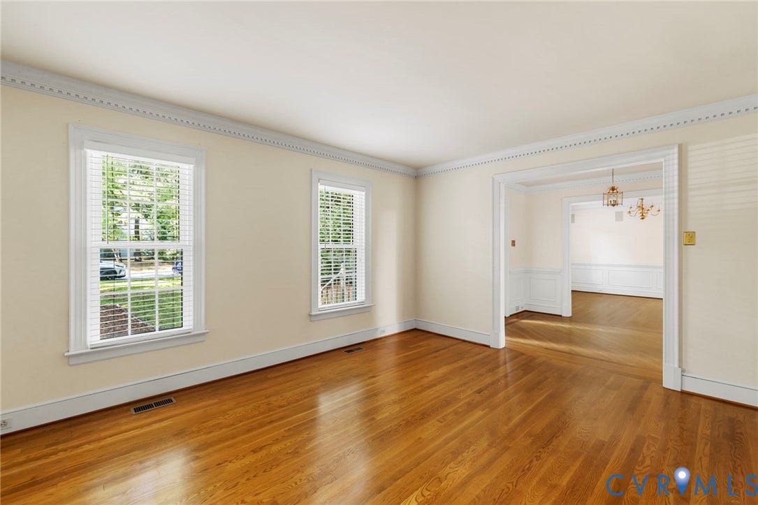 Wood-finish flooring, white window trim, decorative crown molding, and wainscoting