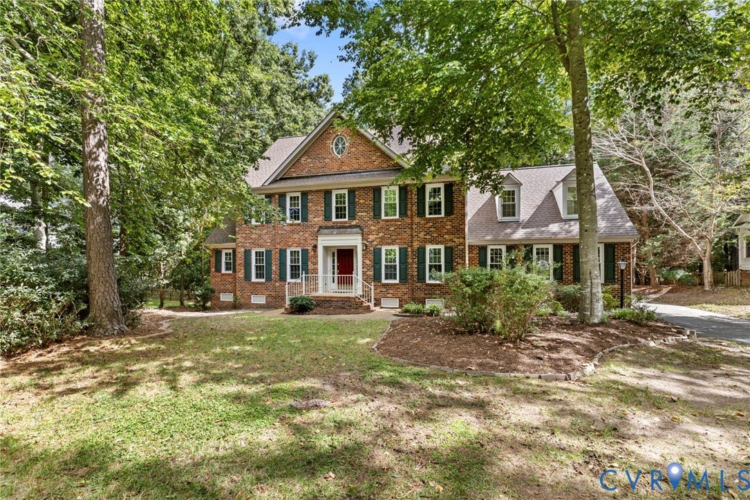 Brick exterior with green shutters, a central red front door, and a dormer window