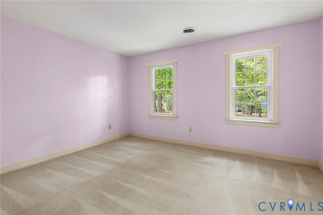 Two windows with white trim, light-colored carpeting, and light purple walls