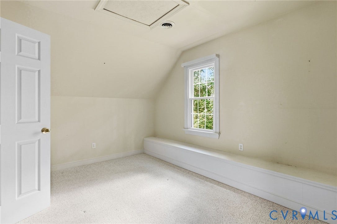 Angled ceiling room featuring a window with natural light, wall-to-wall carpeting, and a built-in storage bench