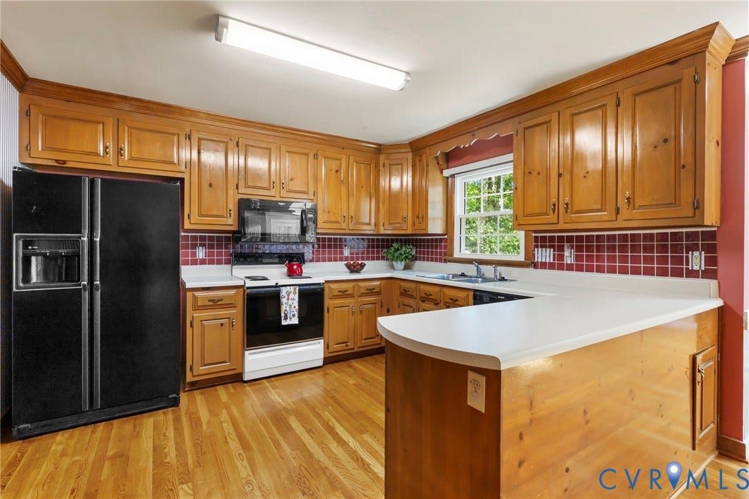 Kitchen featuring wood cabinetry, white countertops, red tile backsplash, and wood-finish flooring