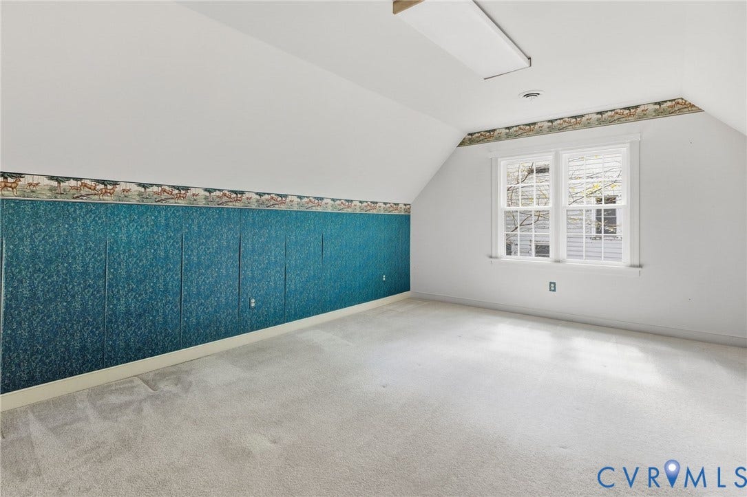 Carpeted flooring, sloped ceiling, window with multiple panes, accent wall with blue textured paneling, ceiling-mounted light fixture