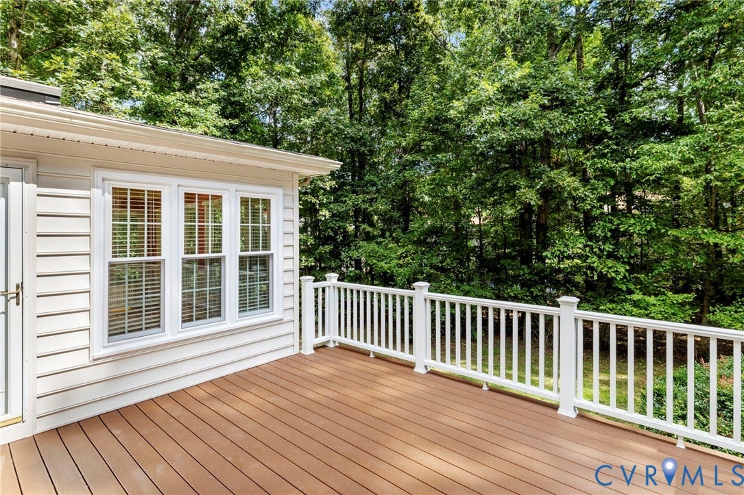 Expansive outdoor deck featuring wood-finish flooring and a white railing system