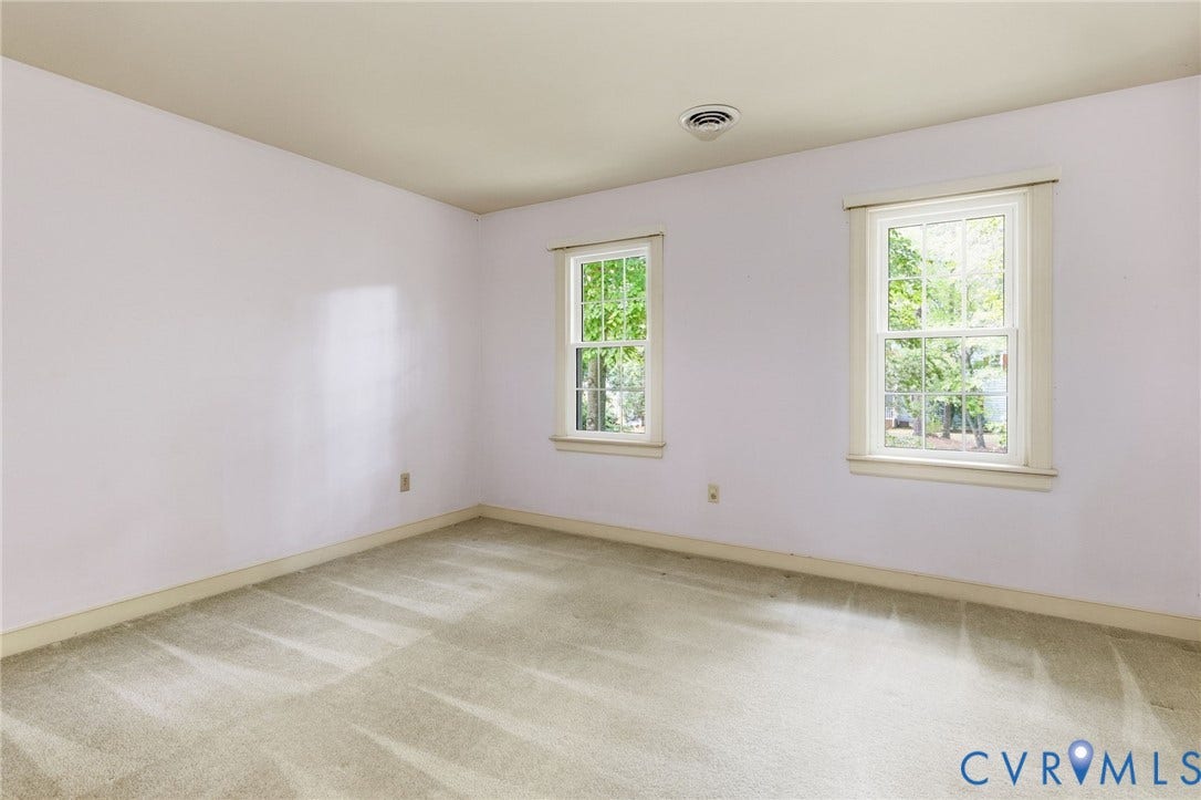 Two windows with white trim, light-colored walls, and neutral carpeting
