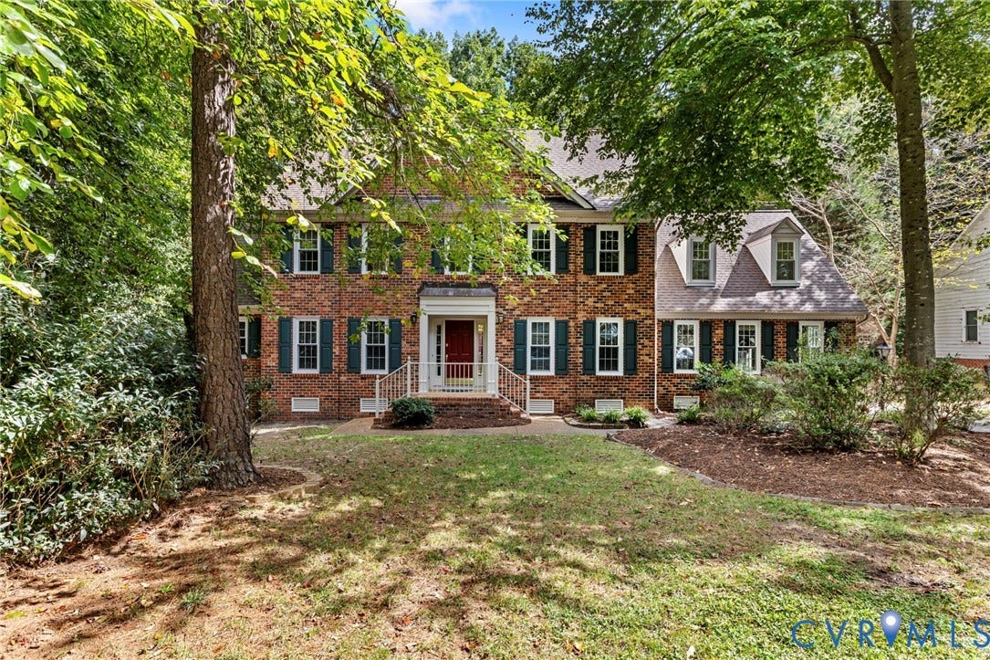 Brick exterior with dark green shutters, white trim windows, and dormer windows
