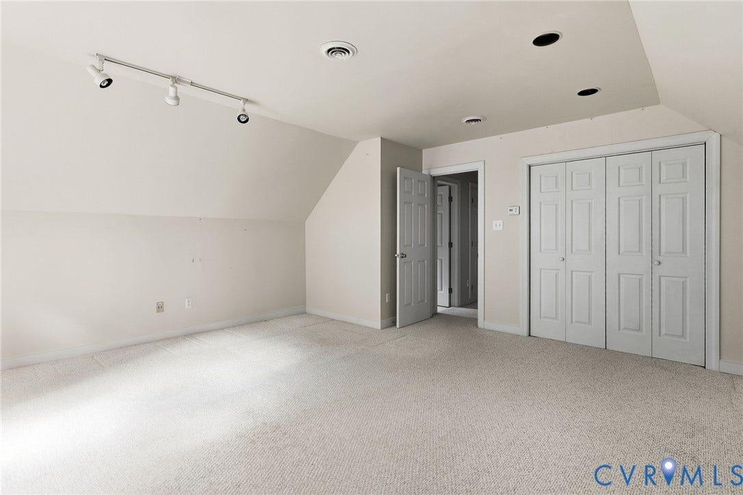 Carpeted room featuring a sloped ceiling, track lighting, recessed lighting, and white bi-fold closet doors