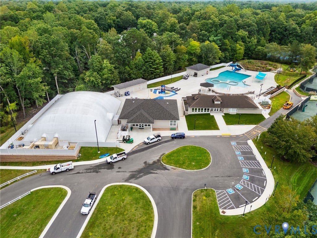 Community clubhouse and recreation area featuring multiple swimming pools, tennis courts, and ample paved parking
