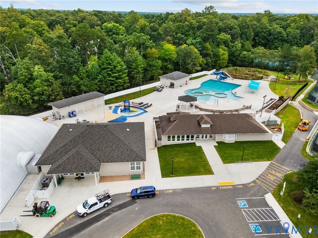 Community recreation area featuring a large swimming pool, separate children's splash pad, multiple tennis courts, and a clubhouse building