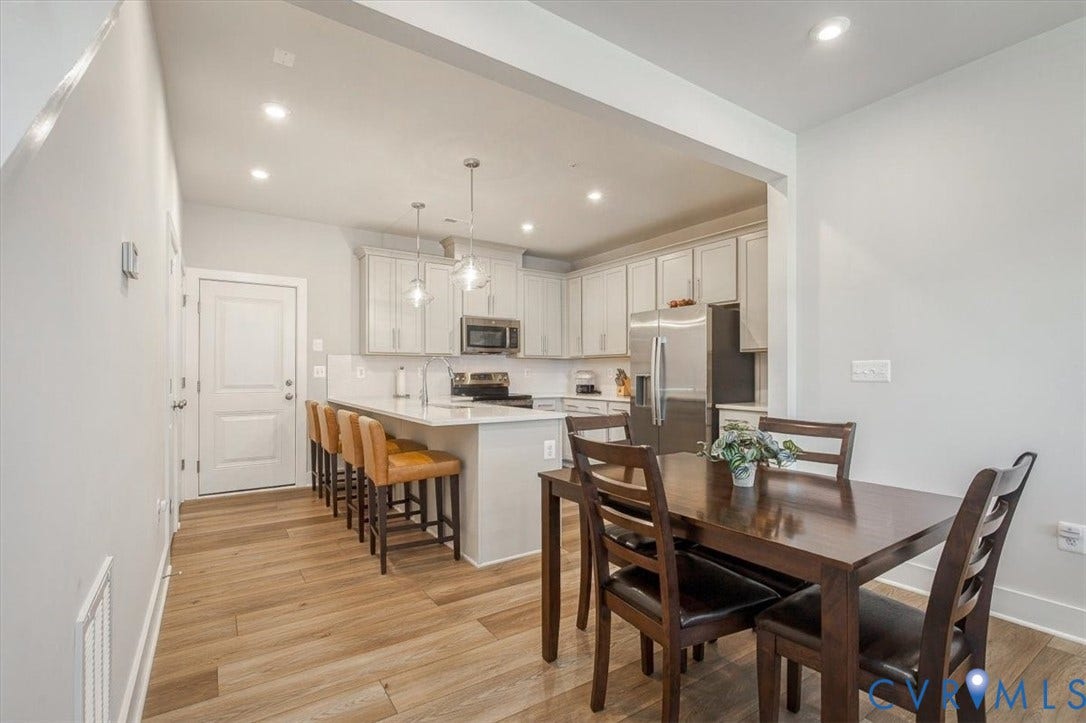 9690 Turning Point Dr, #A, 4E300, Glen Allen, VA 23059 Open-concept kitchen and dining area featuring white cabinetry, stainless steel appliances, quartz countertops, pendant lighting, wood-finish flooring throughout