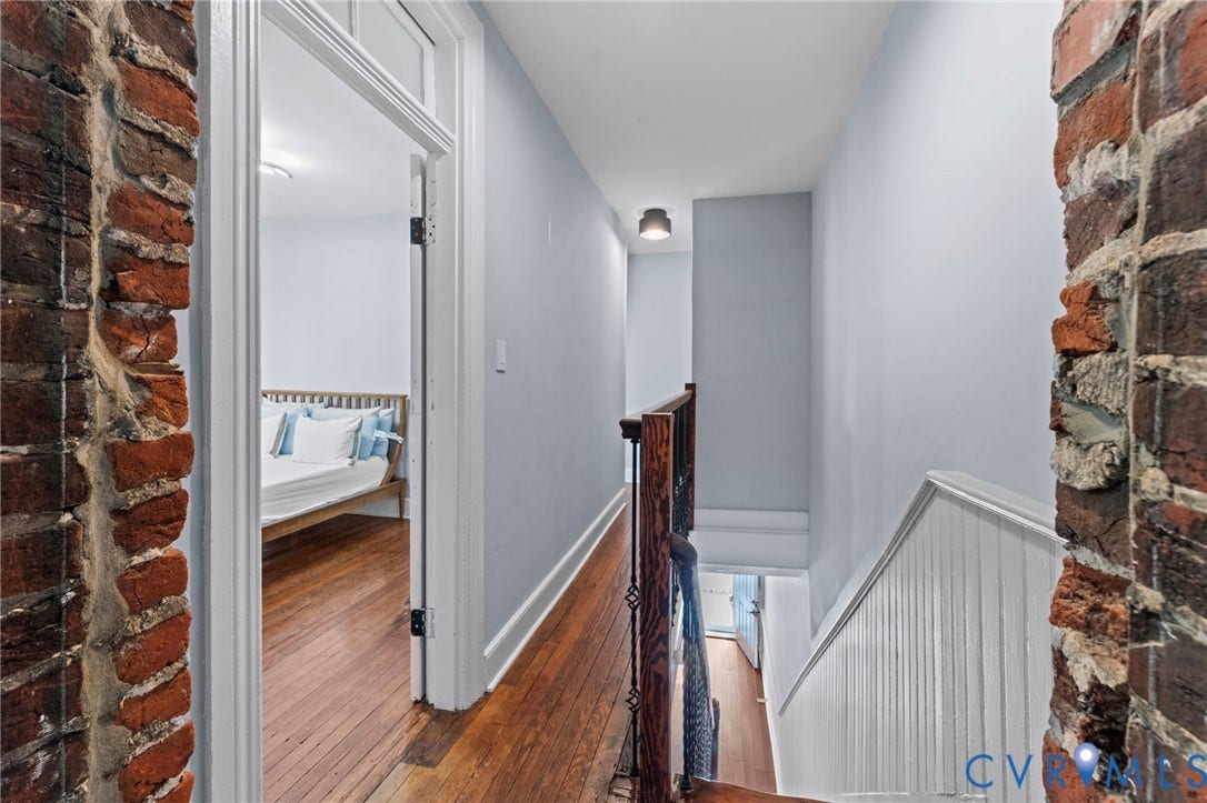 724 N 1st Street, Jackson Ward, Richmond, VA 23219 Exposed brick wall detail, wood-finish flooring, white trim, and a wooden banister