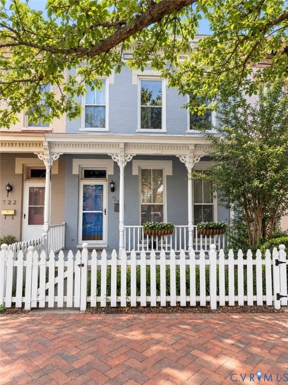 724 N 1st Street, Jackson Ward, Richmond, VA 23219 Brick facade with decorative white trim, featuring a full-width porch with white balusters and ornate columns