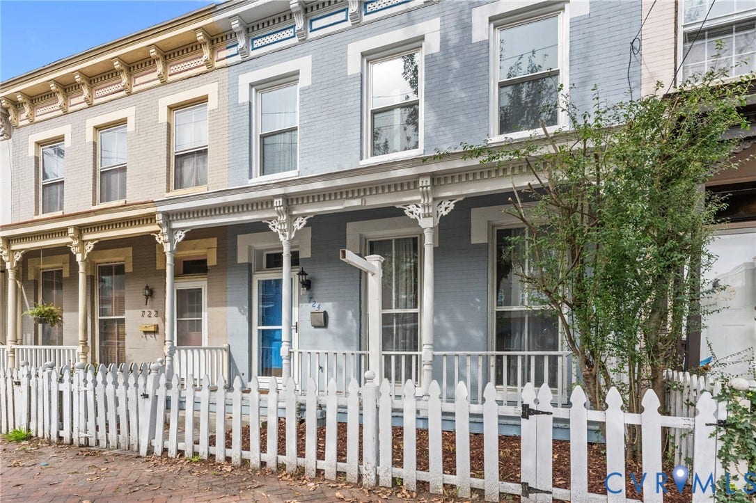 724 N 1st Street, Jackson Ward, Richmond, VA 23219 Brick exterior with a charming front porch, decorative pillars, white picket fence, and a vibrant blue front door