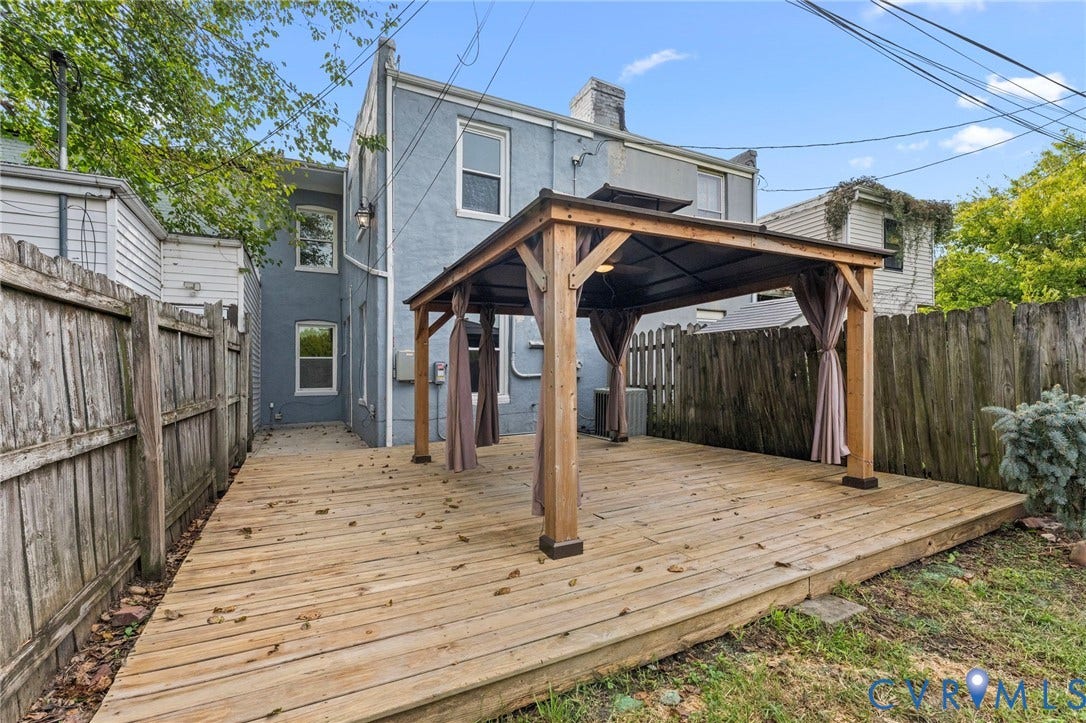724 N 1st Street, Jackson Ward, Richmond, VA 23219 Wood deck with a built-in pergola featuring drapes, surrounded by wood fencing and a stucco exterior
