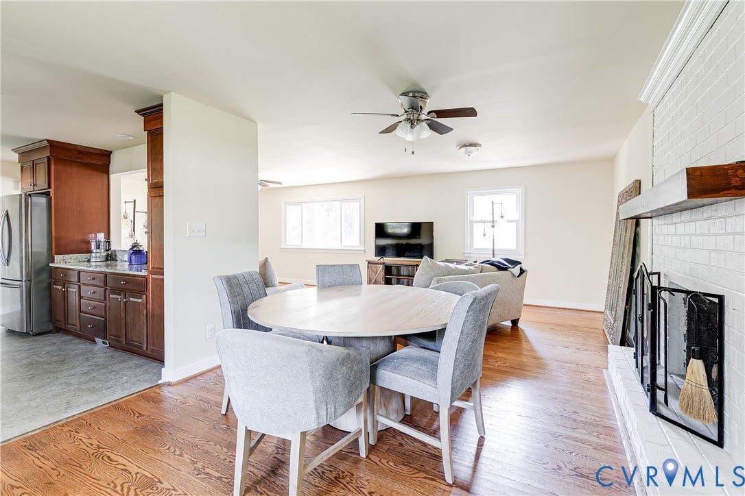 Hardwood flooring complemented by a white brick fireplace with a wood mantle