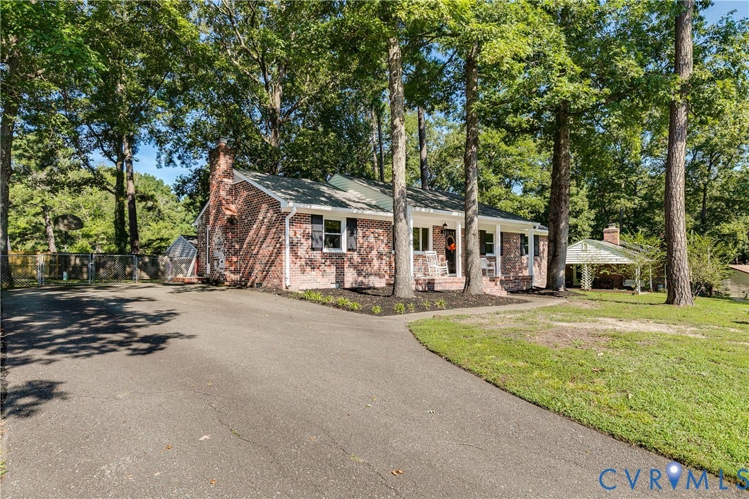 Brick exterior with a prominent chimney, covered front porch, and a paved driveway
