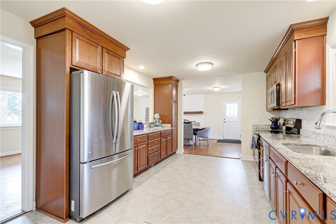 Kitchen featuring stainless steel appliances, wood cabinetry, granite countertops, and tile flooring