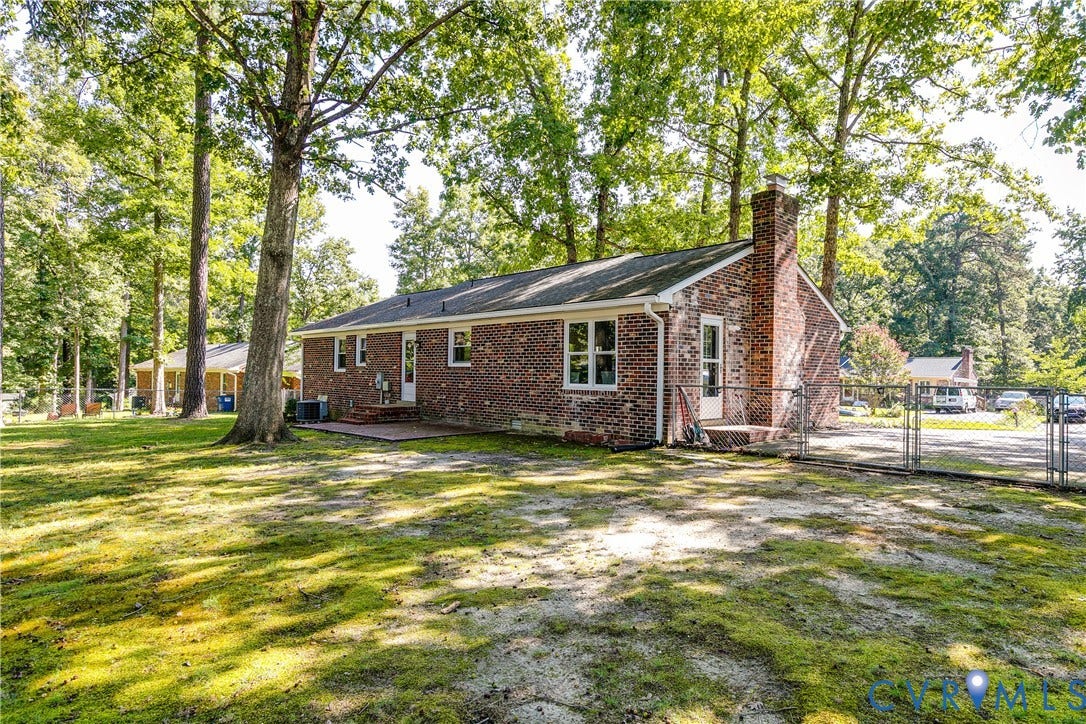 Brick exterior with a prominent chimney, multiple windows, and a rear patio