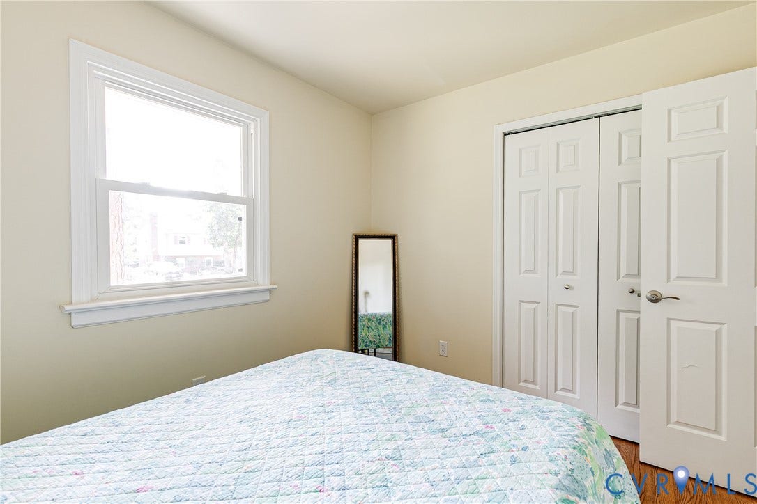 Single-hung window with white trim, bi-fold closet doors, and wood-finish flooring