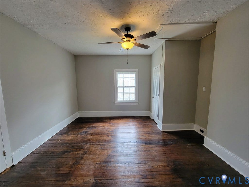1223 Paul Street, Hillcrest, Petersburg, VA 23803 Spacious room showcasing rich wood-finish flooring, neutral wall finishes, and abundant natural light from a large window