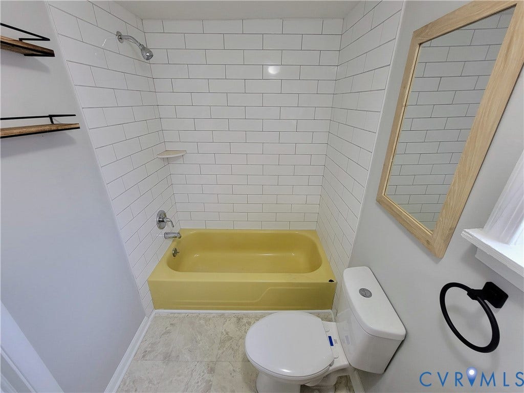 1223 Paul Street, Hillcrest, Petersburg, VA 23803 Compact bathroom featuring white subway tile walls, a yellow fiberglass bathtub with integrated shower, low-profile toilet, recessed ceiling lighting, a wood-framed mirror, and tile flooring