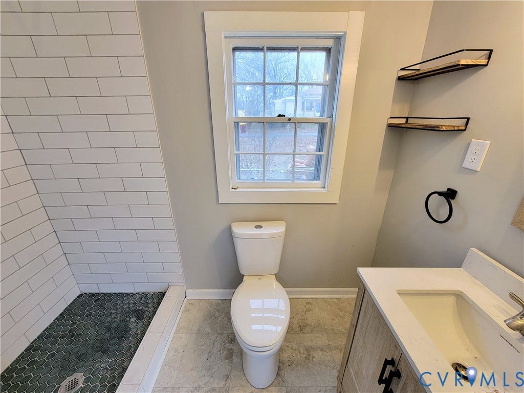 1223 Paul Street, Hillcrest, Petersburg, VA 23803 Updated bathroom featuring subway tile shower surround, porcelain toilet, floating vanity with integrated sink, matte black hardware accents, and natural light from operable window