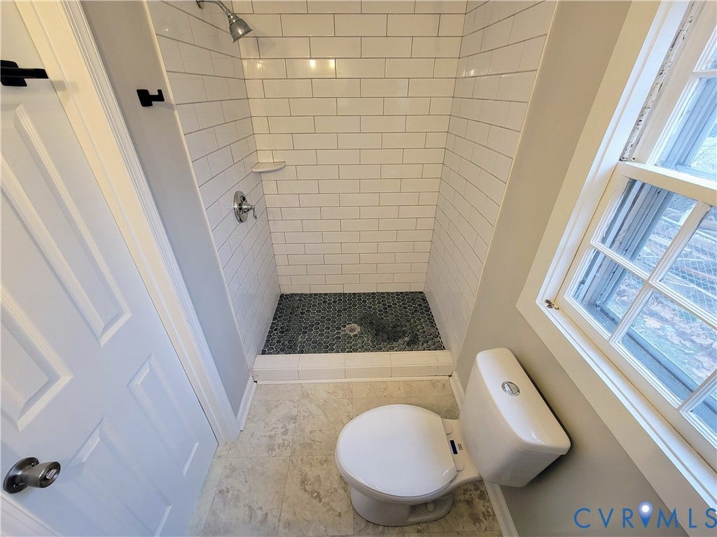 1223 Paul Street, Hillcrest, Petersburg, VA 23803 Shower with white subway tile surround, dark hexagonal tile shower floor, and a single-pane window