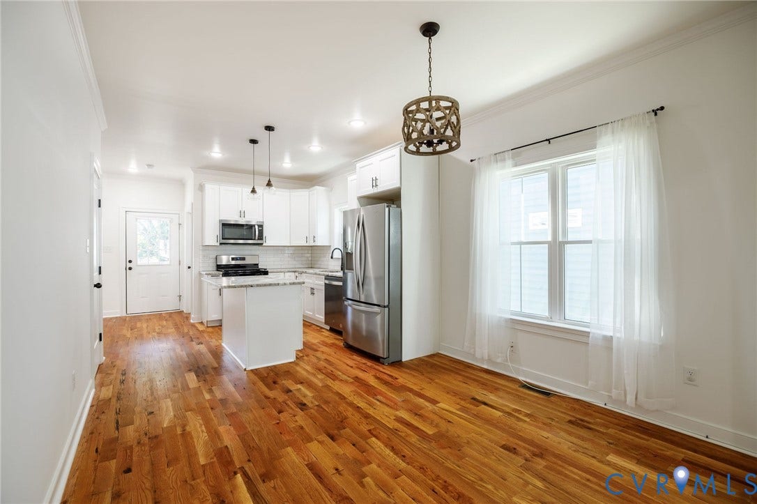 2902 Lawson Street, Richmond, VA 23224 Kitchen featuring wood-finish flooring, white cabinetry, a center island with stone-finish countertops, stainless steel appliances, and decorative pendant lighting