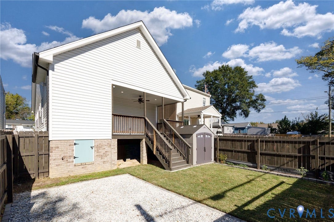 2902 Lawson Street, Richmond, VA 23224 Vinyl siding exterior featuring a covered porch, wood-style staircase with railings, gravel patio area, and enclosed backyard with wood fencing