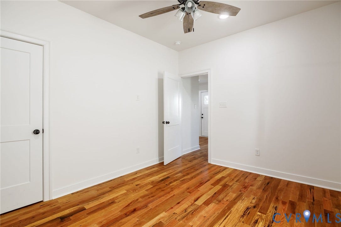 2902 Lawson Street, Richmond, VA 23224 Interior space featuring wood-finish flooring, white walls, two-panel interior doors with black hardware, and a ceiling fan with integrated lighting