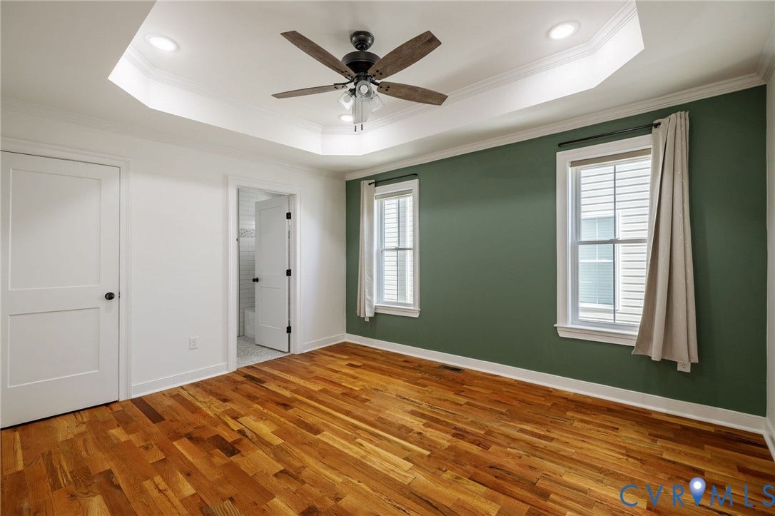 2902 Lawson Street, Richmond, VA 23224 Tray ceiling featuring a central ceiling fan with integrated lighting, wood-finish flooring, and two double-hung windows
