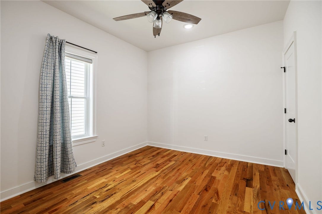 2902 Lawson Street, Richmond, VA 23224 Room featuring wood-finish flooring, a multi-blade ceiling fan with integrated lighting, and a single-hung window with a roller shade