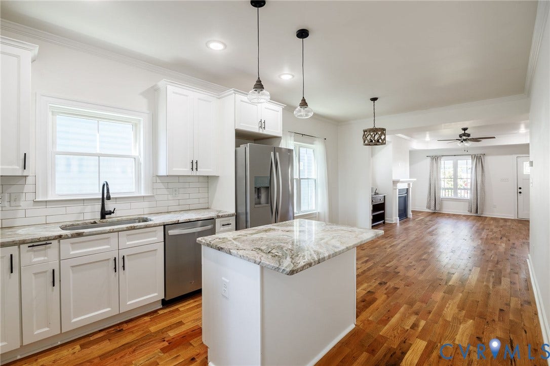 2902 Lawson Street, Richmond, VA 23224 Kitchen featuring white shaker cabinetry, stone-surface countertops, subway tile backsplash, center island, and wood-finish flooring