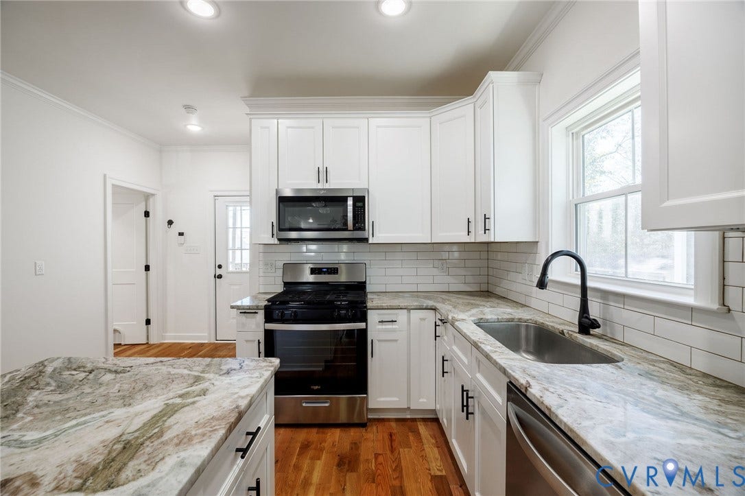 2902 Lawson Street, Richmond, VA 23224 Kitchen featuring white shaker-style cabinetry, stone-patterned countertops, subway tile backsplash, stainless steel appliances, and wood-finish flooring
