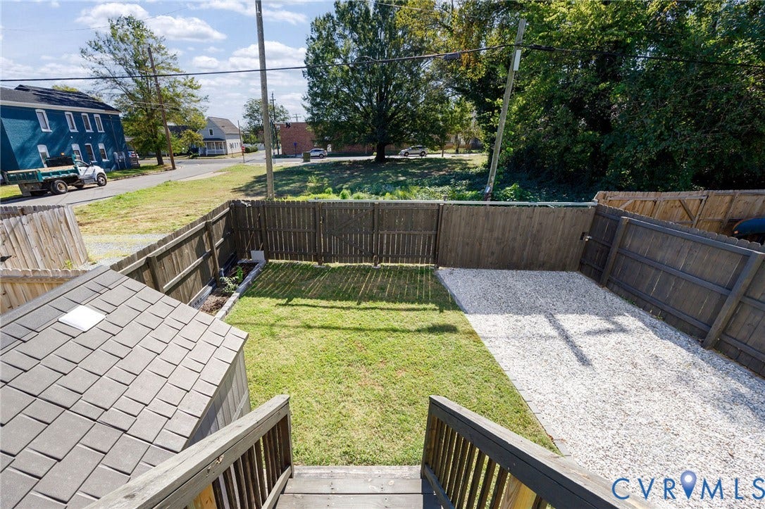 2902 Lawson Street, Richmond, VA 23224 Enclosed backyard featuring wood fencing, a grass lawn, gravel surfacing, and a shingle-roofed exterior structure