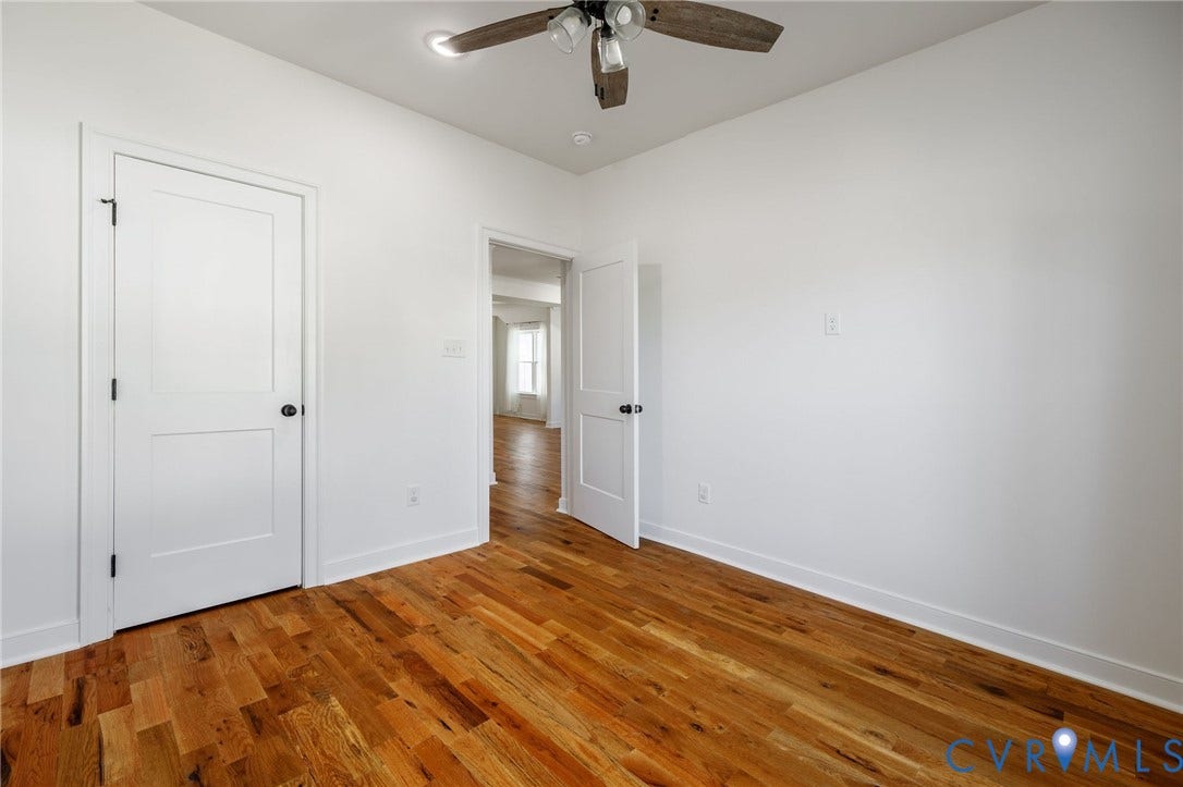 2902 Lawson Street, Richmond, VA 23224 Room featuring wood-finish flooring, two-panel shaker-style interior doors with matte black hardware, and a ceiling-mounted light fixture with a fan