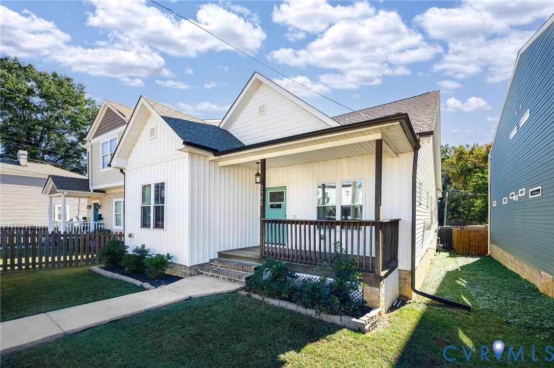 2902 Lawson Street, Richmond, VA 23224 Vertical board-and-batten siding exterior featuring a covered front porch, dark-stained wooden railings, and a concrete walkway