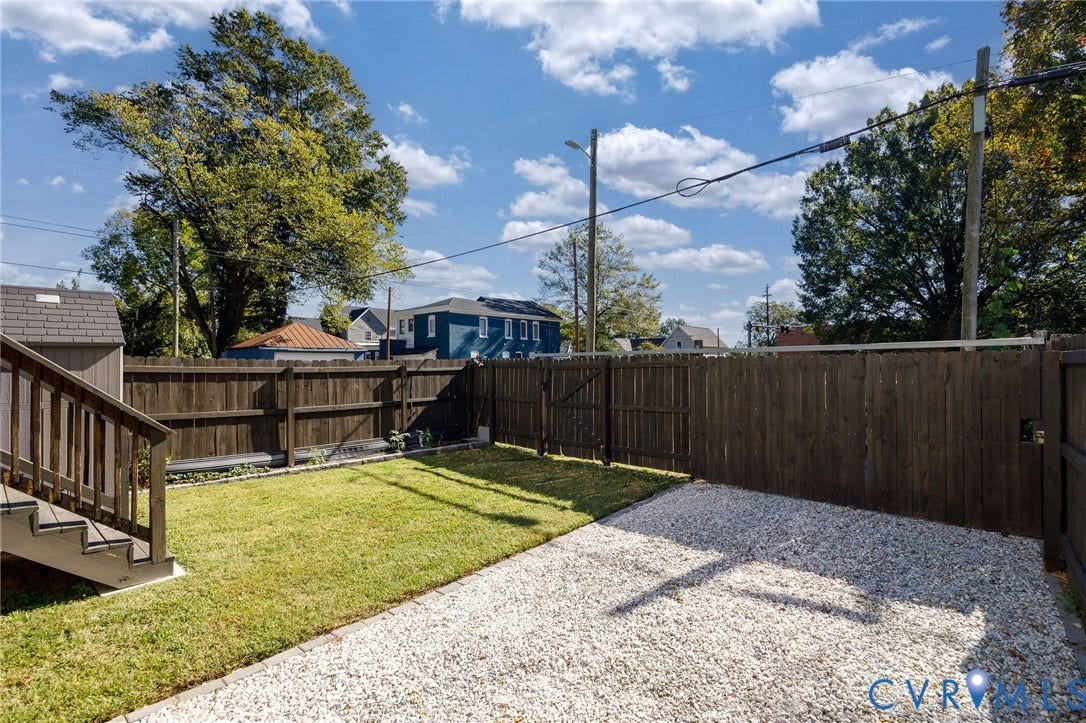 2902 Lawson Street, Richmond, VA 23224 Backyard featuring a grass lawn, gravel patio area, wooden privacy fencing, and exterior staircase
