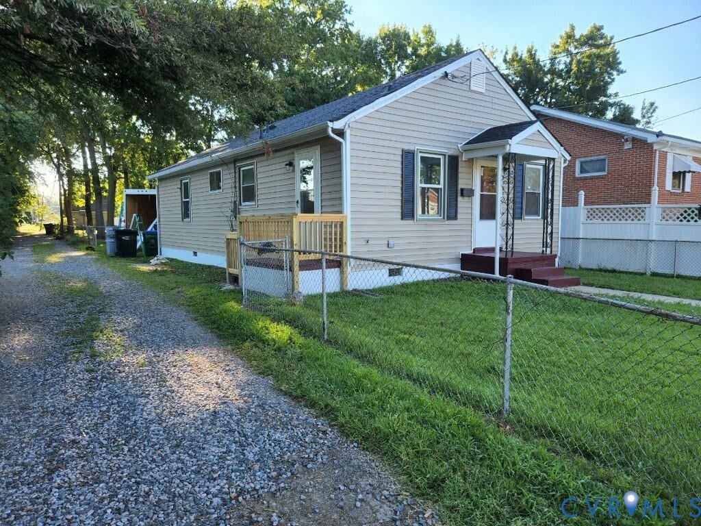 Single-story residence featuring light-colored siding, a covered front porch with wrought iron supports, and a gravel driveway