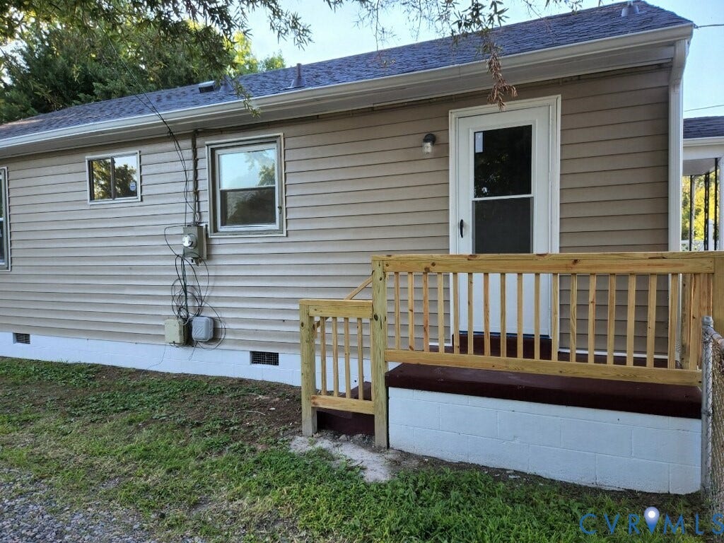 Tan vinyl siding exterior with white trim windows and a new wood deck