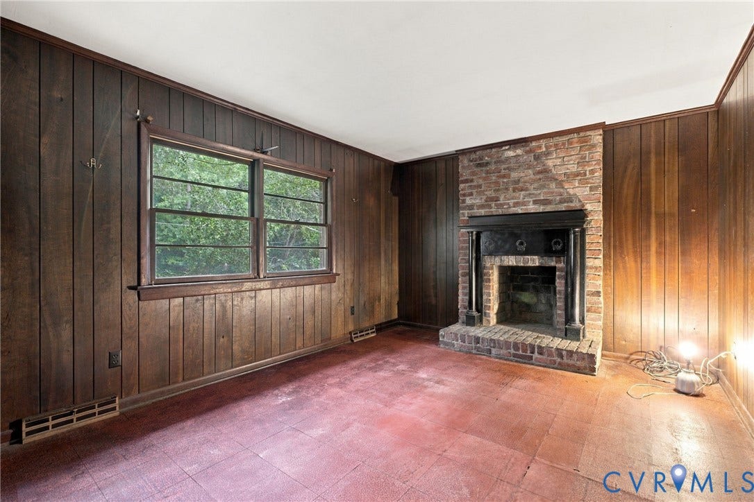 8150 Bradbury Road, Henrico, VA 23231 Brick fireplace with a dark wood mantel and surround, wood paneling, and a dual-pane window