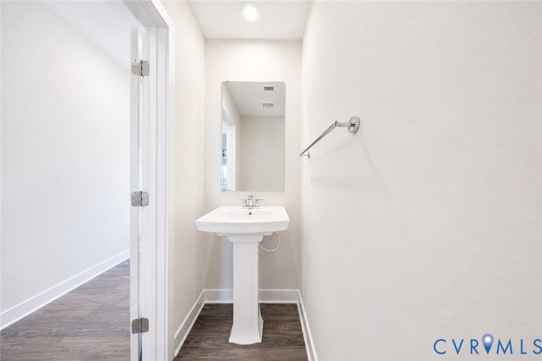 10607 Pink Lilly Lane, Chester, VA 23831 Pedestal sink with chrome faucet, framed mirror, and wood-finish flooring