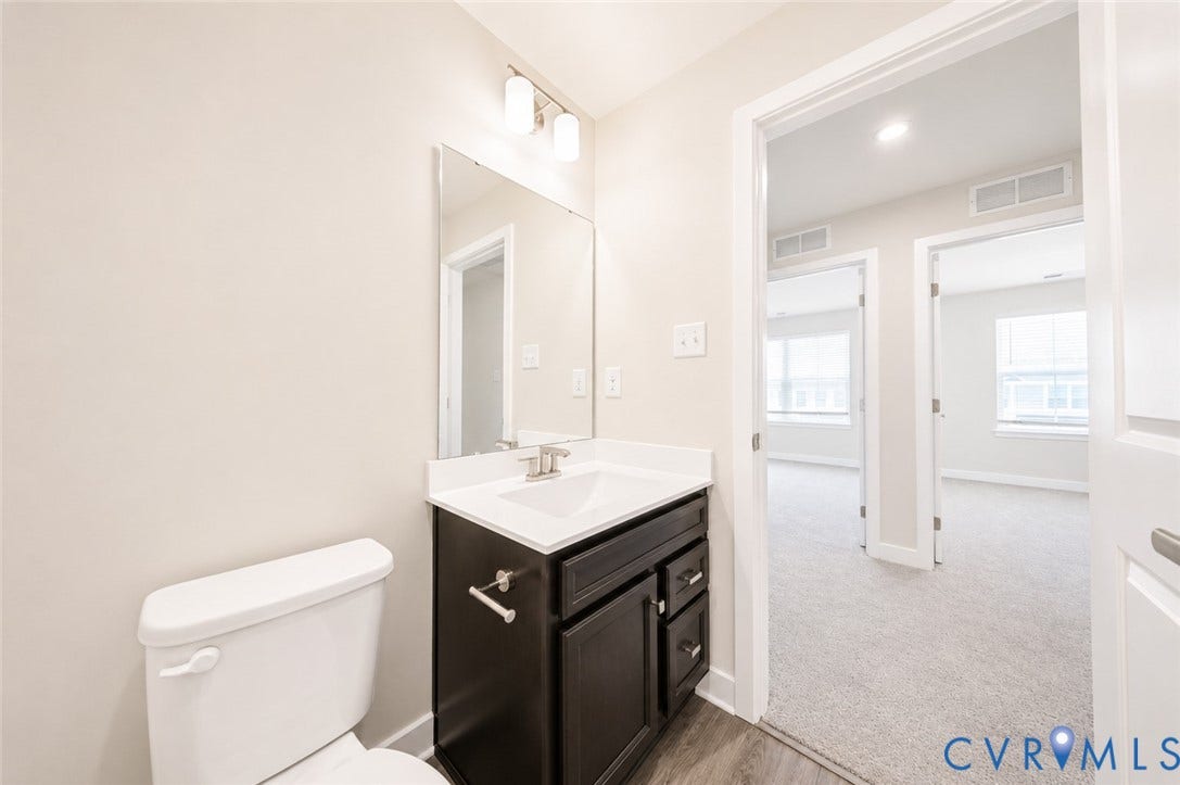 10607 Pink Lilly Lane, Chester, VA 23831 Bathroom vanity with an integrated sink and brushed nickel faucet, mirror, wall-mounted light fixture, and wood-finish flooring