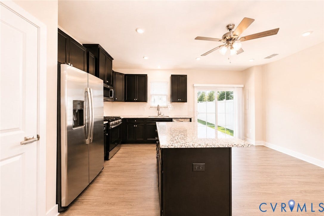 10607 Pink Lilly Lane, Chester, VA 23831 Kitchen featuring dark wood-finish cabinetry, stainless steel appliances, a center island with a light-toned countertop, and wood-finish flooring